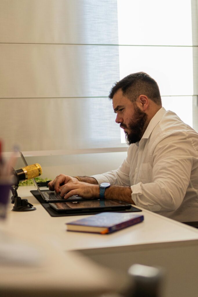Businessman intently working on a laptop at a modern office desk, showcasing focus and productivity.
