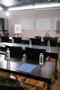 A neatly arranged conference room with tables, chairs, water bottles, and stationery ready for a meeting.