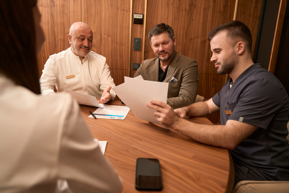 physicians discussing papers with man at desk fexh47d.jpg